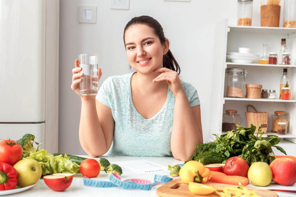 Mujer con sobrepeso bebiendo agua para hidratarse